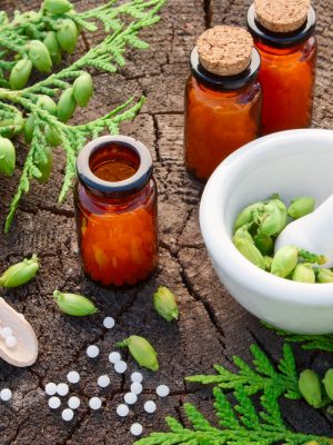 Bottles of homeopathic globules, Thuja occidentalis drugs, mortar and pestle. Homeopathy medicine concept.